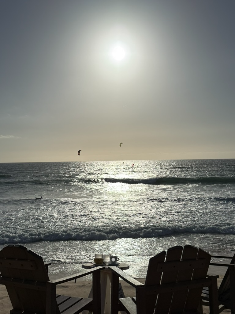 Kitesurfers off the beach with coffee on a beachfront table