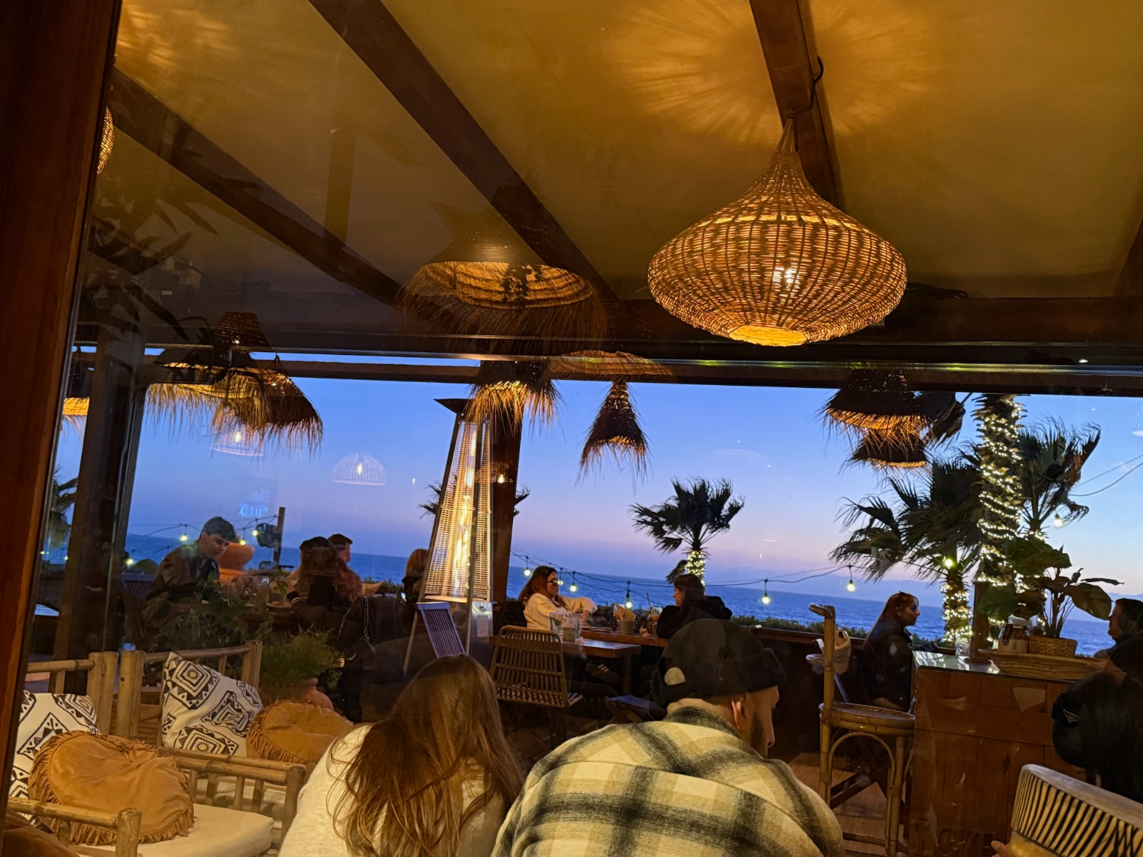 Beach bar at blue hour with rattan lamps and sea view