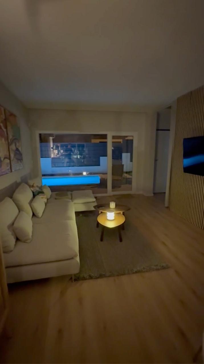 Living room in the evening with warm lamp light and view to the lit pool