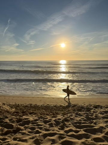 Surfer at sunset on the beach near Fonte da Telha